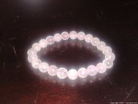 Full view of rose quartz beaded bracelet on dark surface