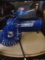 Side view of Campbell Hausfeld air compressor with coiled hose attached