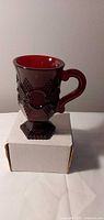 Front view of ruby red Avon pedestal mug, showing handle and pattern