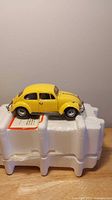Left side view of yellow 1:24 Volkswagen Beetle model on foam packaging