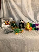 Overall lot showing silver case, four visible plush toys, outfit pieces