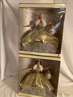 Front view of both boxed dolls stacked, showing full packaging and outfits