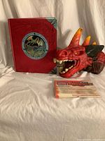 Dragonology book, red dragon puppet, Firedrake instruction sheet on white backdrop
