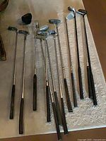 Twelve golf clubs laid out on floor