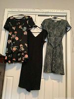 Front view of three dresses: floral, black V-neck, grey-green patterned