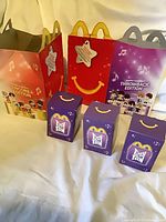 Group shot showing both Happy Meal boxes and three purple TinyTAN toy boxes