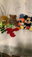 Group shot of eight assorted plush toys on white backdrop