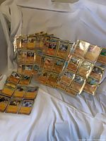 Group of binder pages filled with orange-border Pokémon cards on white backdrop