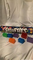 Smarties metal coin bank and seven assorted colour plastic building blocks