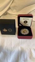 Coin in open clamshell case with COA and outer box