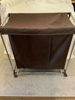 Front view of brown canvas hamper on metal frame with casters