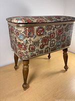 Full view of sewing stool front showing tapestry upholstery and turned legs