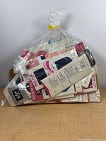 Bagged lot of assorted packaged sewing notions front view