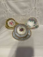 Front view of three mismatched floral teacup and saucer sets