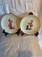 Front view of both M.J. Hummel plates on stands