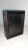 Front view of closed black wooden key box with glass door