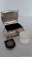 Open silver-plated box showing velvet interior, milk glass jar, compact