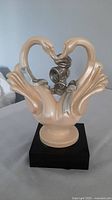 Full view of ceramic swan pair on black base