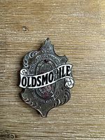 Front of Oldsmobile radiator badge showing text and enamel