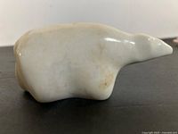 left side view of white stone polar bear carving