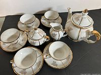 Full view of complete porcelain tea set showing teapot, sugar bowl, creamer, 4 cups and 4 saucers