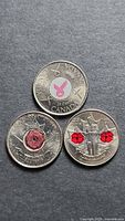 Fronts of three colourized commemorative quarters showing ribbon and poppy designs