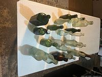 Seventeen assorted vintage bottles laid out on table showing size and color range