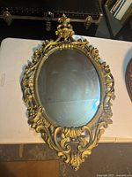 Front view of ornate oval gold-tone mirror