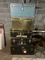 Stack of five vintage trunks showing colors and hardware