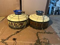 Both Arrow advertising hanging lamp shades with chains visible