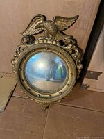 Full view of convex eagle mirror leaning against wall