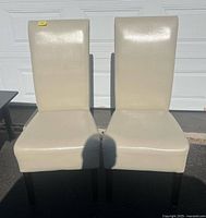 Front view of both cream faux leather dining chairs