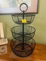 Full view of the 3-tier black metal fruit basket on tabletop