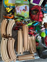 Overview of wooden train tracks, vehicles, puzzle, Spiderman mask and accessories