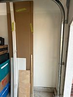 Tall MDF and trim boards, plywood panels and dowels stacked against wall