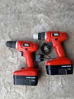 Two red 18V Black & Decker cordless drills with batteries and charger