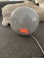 Front view showing spherical clock, red LED time display and USB cable