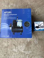 Front view of AF186 compressor retail box and cleaning pot box