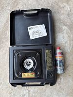 Stove inside open carrying case with manual and one fuel canister