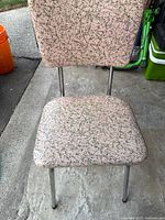 Front view of chair showing pink vinyl with green crackle pattern, seat, legs