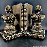 Front three-quarter view of both bookends showing urn motif and scroll bases