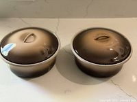 Two enamel casseroles with lids side by side showing color and shape