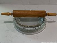 Rolling pin resting on stacked clear glass pie plates