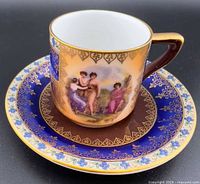 Cup on saucer showing painted scene, gold trim and saucer design