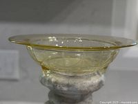 Side profile of amber footed bowl showing rolled rim and feet