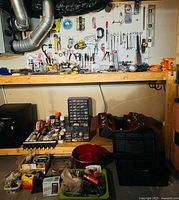 Wide shot of shelving with pegboard full of hand tools, toolboxes, small parts cabinet and bins