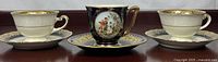 Front view of three demitasse sets showing cup designs and saucers