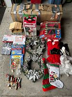 Lot overview showing tree box, flamingo box, Santa suit boxes, wreaths, nativity figures, books, stockings and lights
