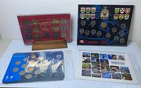 Overview of four commemorative coin boards: red Floral Emblems, black Canada 125, blue Vancouver 2010, white Vancouver 2011