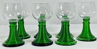 Front view of all eight goblets showing green stems and clear bowls